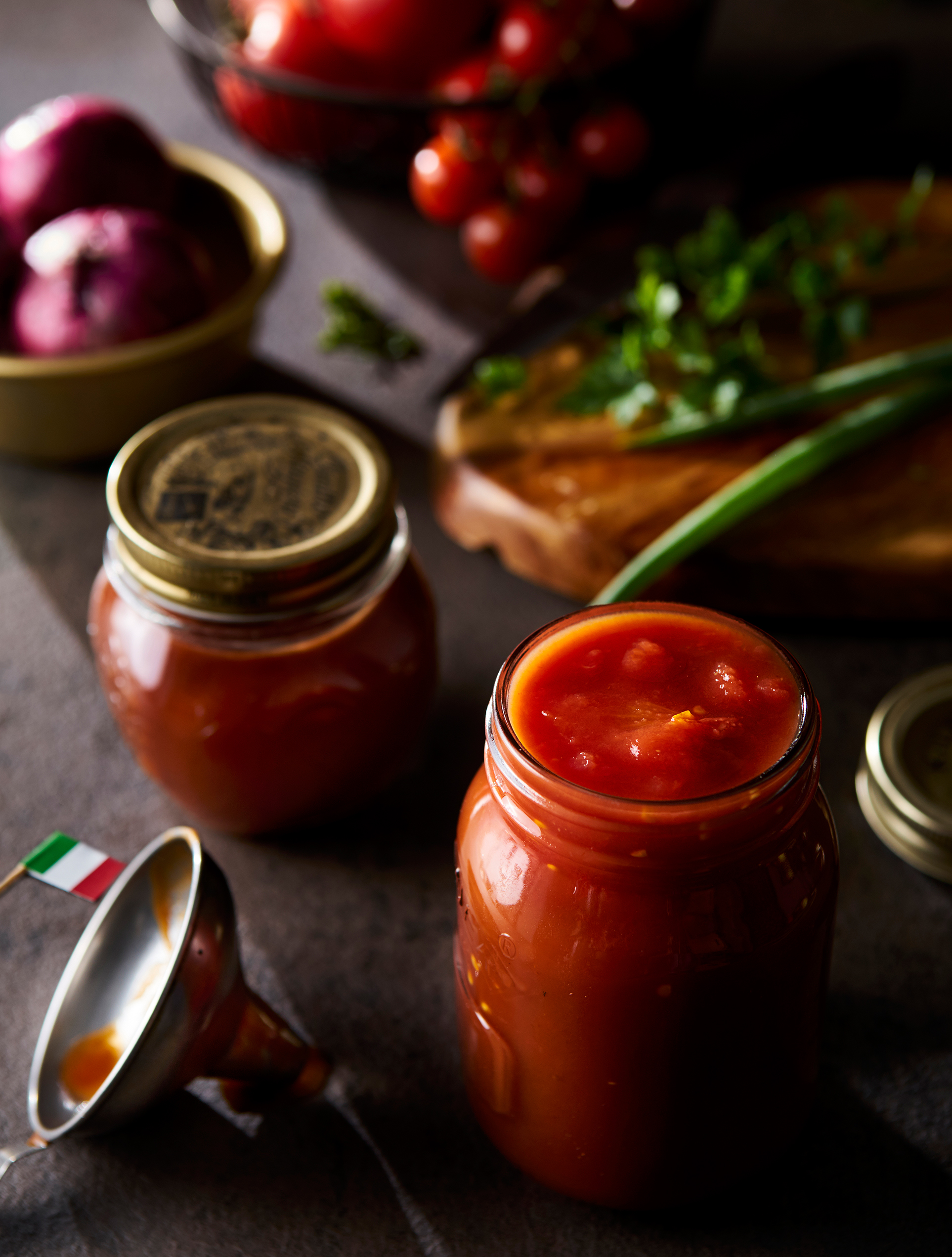 mesa repleta de tomates, cebolas, cheiro verde e molho de tomate, com uma bandeira da italia