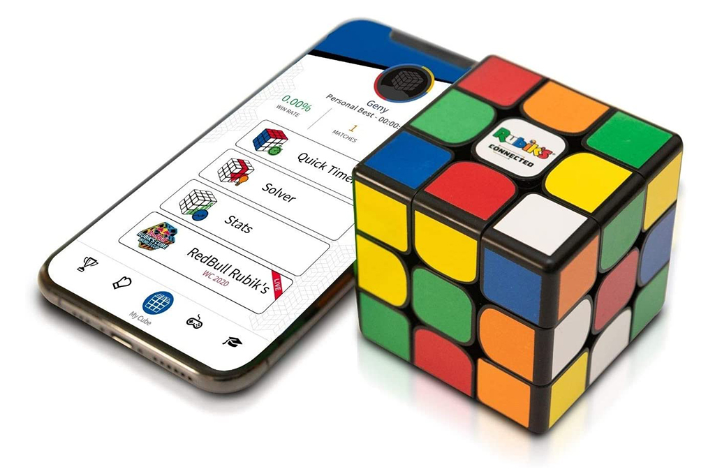 Foto Rubik&rsquo;s Connected Cube ao lado de um celular.