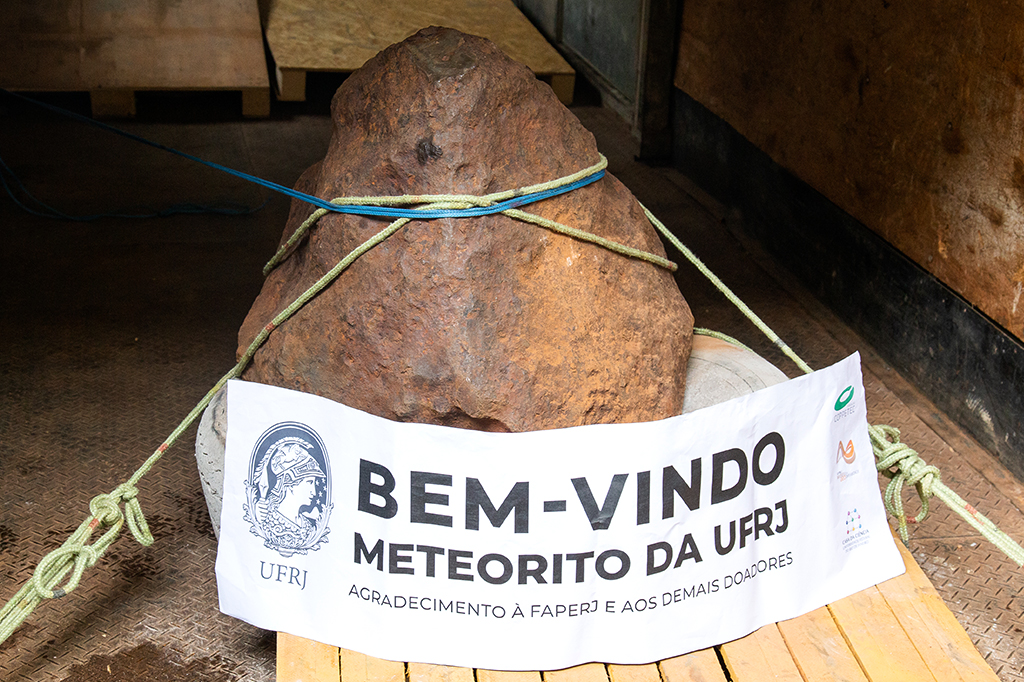 Foto do meteorito com uma faixa com o texto 