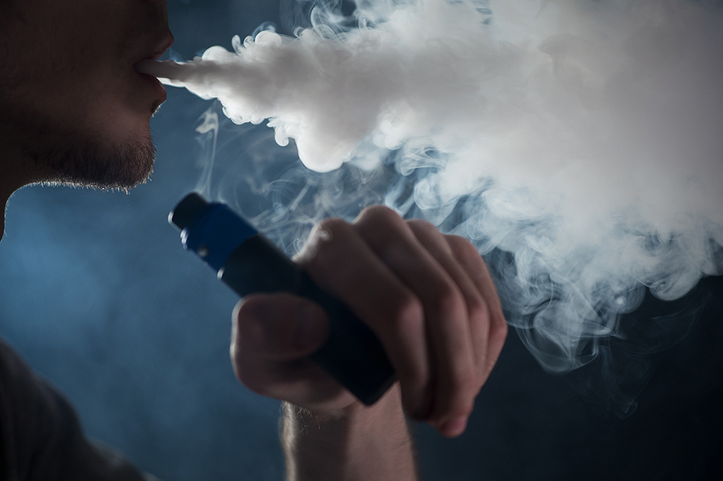 Homem fumando um cigarro eletrônico.