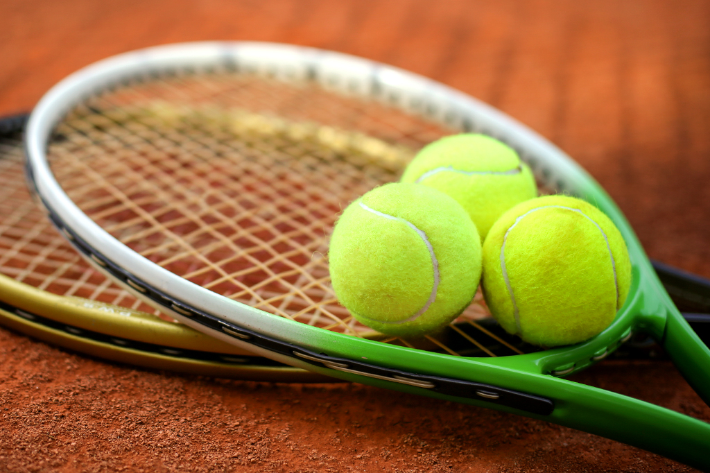 Foto de duas raquetes de tênis com três bolas em cima dela.