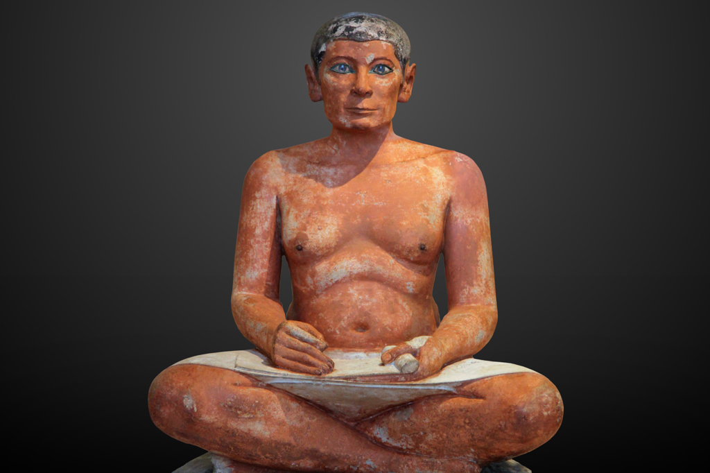 Escultura de um escriba egípcio sentado escrevendo em um pergaminho.