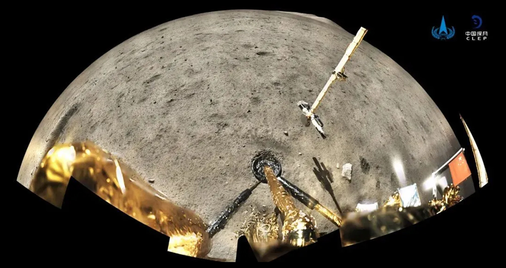 Um panorama retornado pela sonda Chang'e-5, mostrando o braço robótico de amostragem e marcas de escavação no regolito lunar.