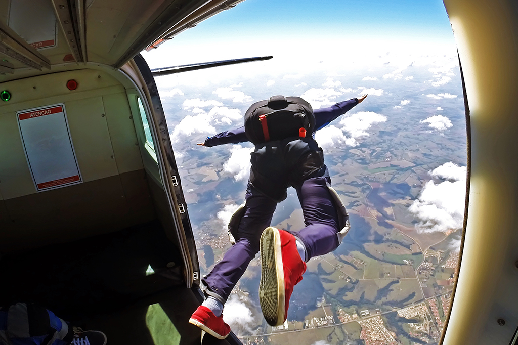 Uma pessoa saltando de um avião de paraquedas.
