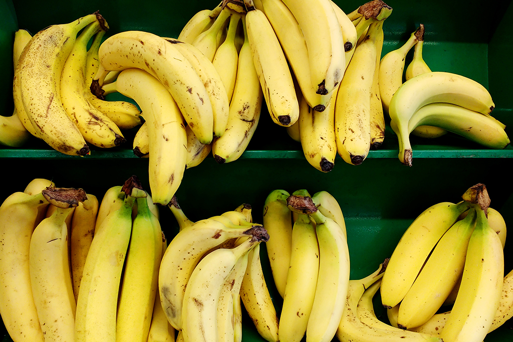 Bananas em prateleira de cor verde.