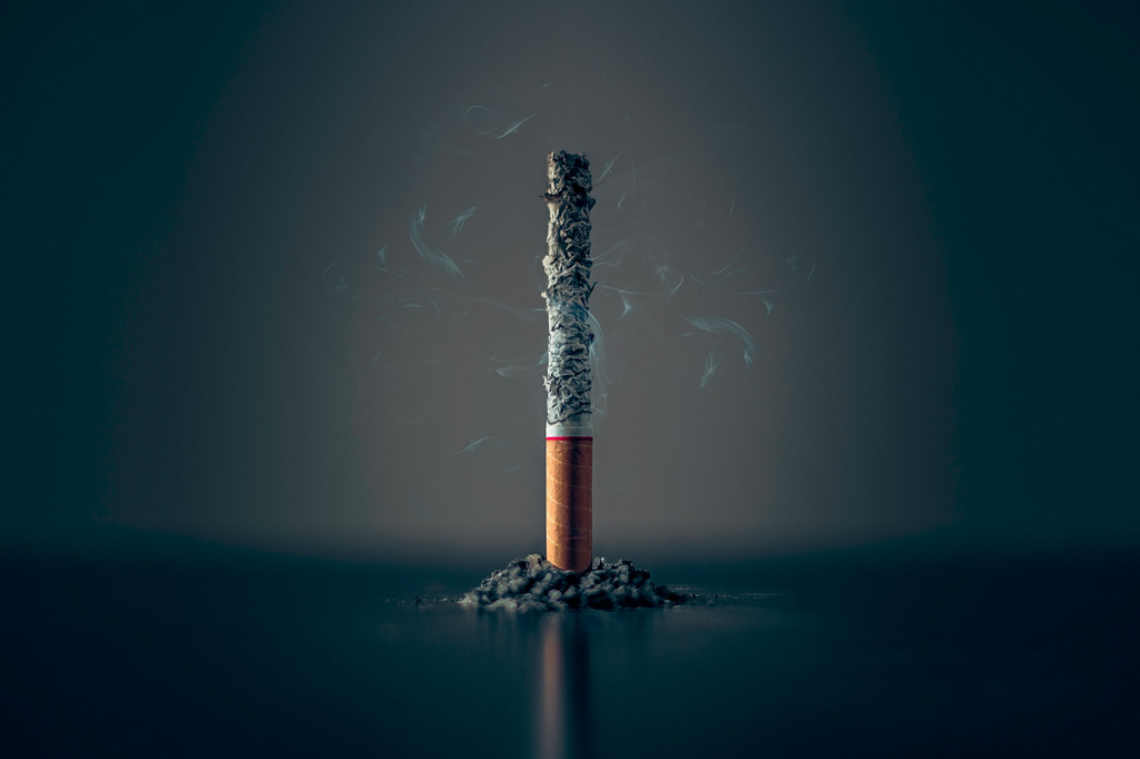 Foto de cigarro em pé consumido pela brasa.