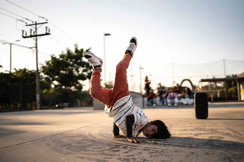 Foto do menino da criança que dança de breakdance no parque de skate