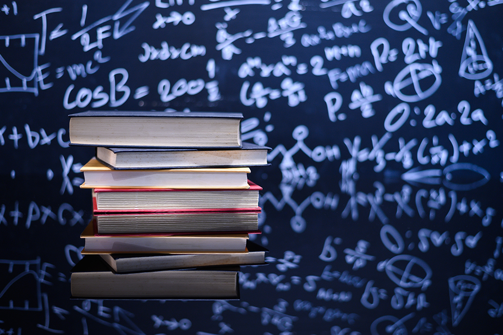 Foto um fundo azul com fórmulas científicas e cálculos em física e matemática e uma pilha de livros na frente.