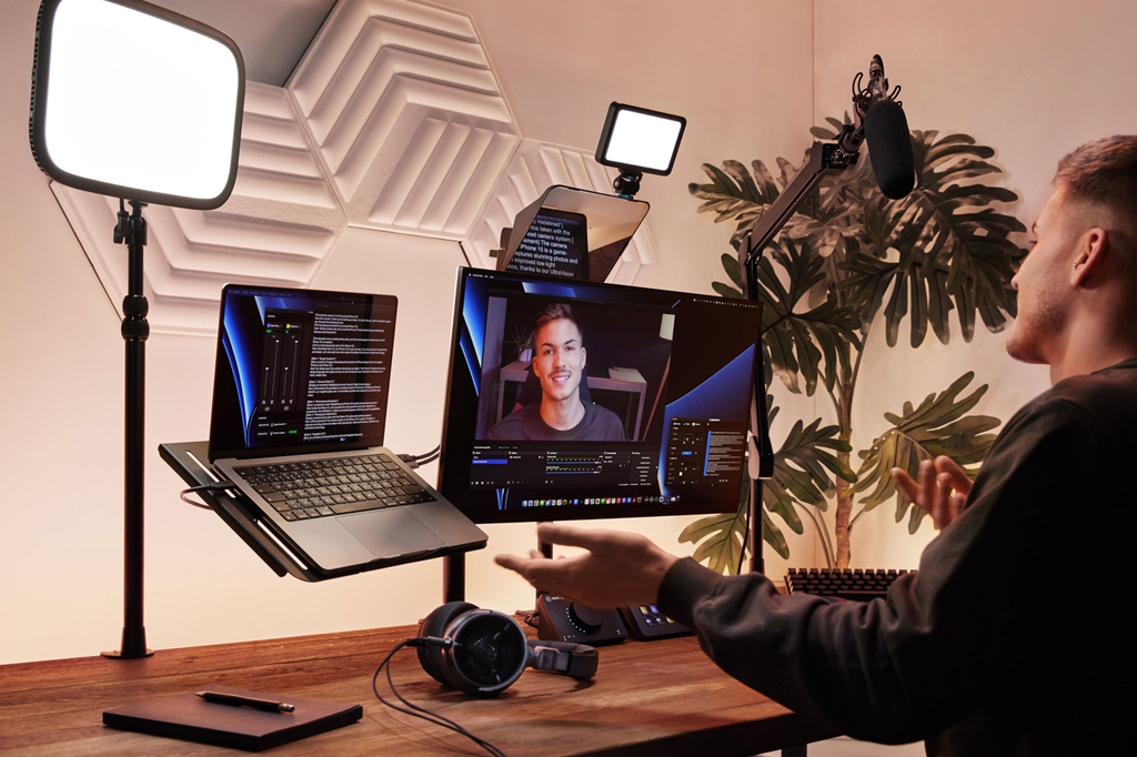 Imagem de um rapaz usando um computador e uma tela de teleprompter.