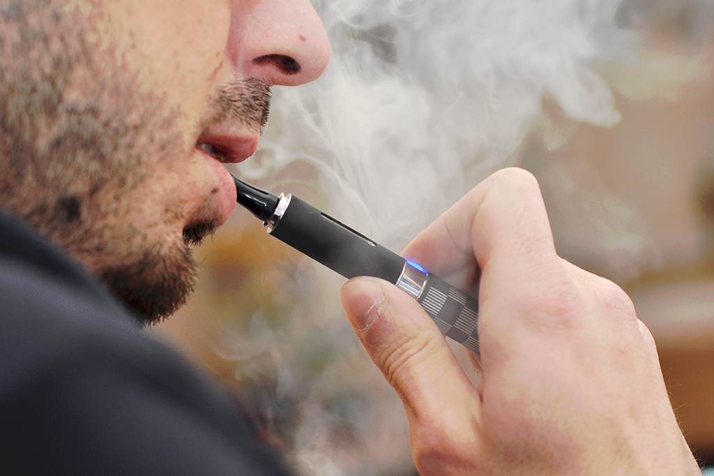 Imagem de um homem fumano cigarro eletrônico.