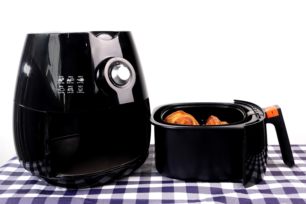 Imagem de uma air fryer desligada em cima de uma toalha quadriculada.