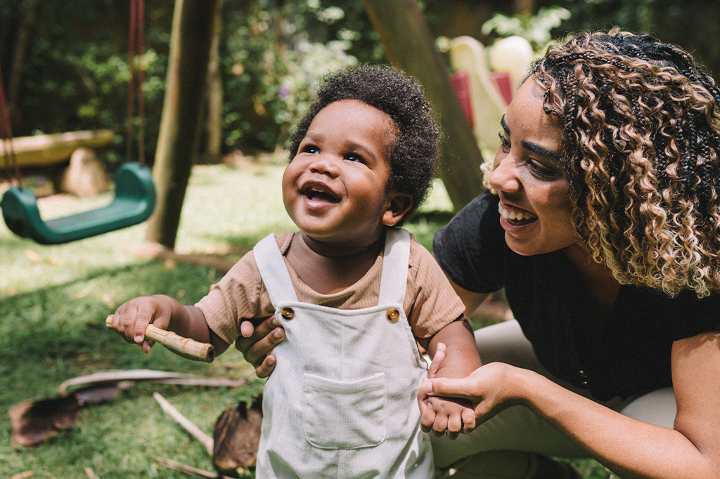 Fotografia de uma mãe e seu bebê se divertindo no playground.
