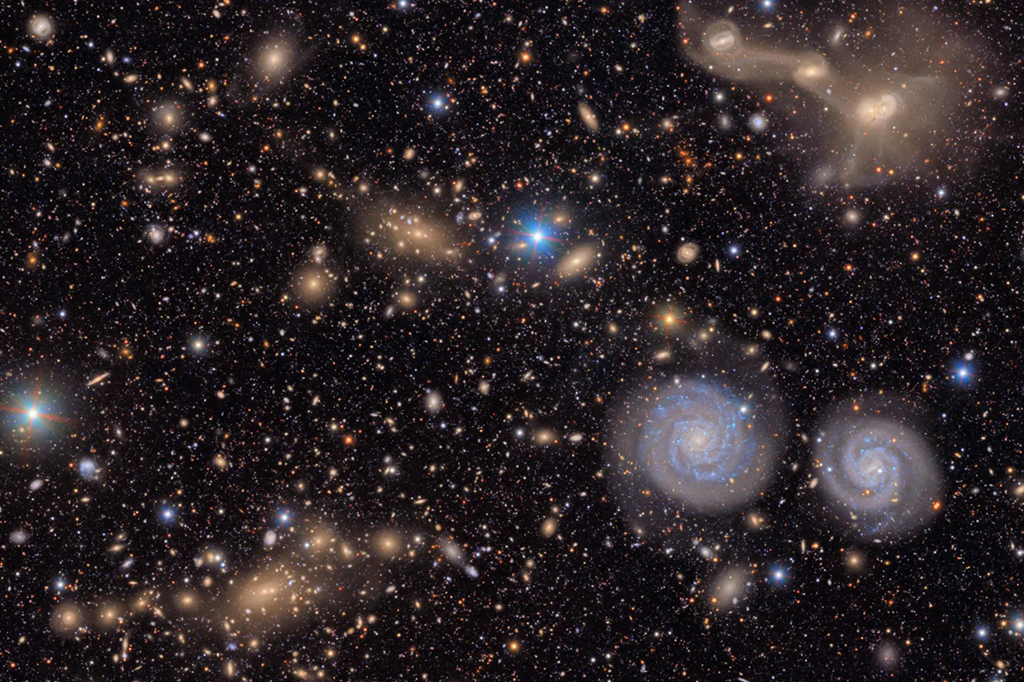 Fotografia de duas gal&aacute;xias espirais proeminentes (abaixo &agrave; direita), tr&ecirc;s gal&aacute;xias em fus&atilde;o (acima &agrave; direita) no aglomerado de Virgem, bem como v&aacute;rios grupos de gal&aacute;xias distantes, muitas estrelas na Via L&aacute;ctea.