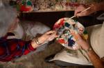 Visão superior de dois idosos compartilhando um godê de pintura com as mãos.