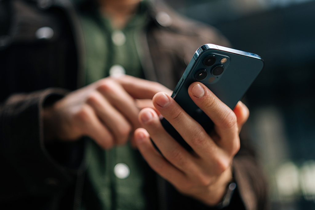 Fotografia e um homem mexendo no celular.