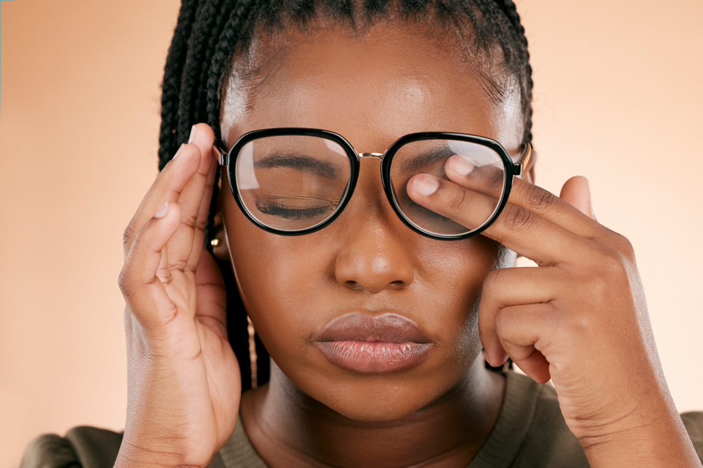 Imagem de uma mulher usando óculos e coçando um dos olhos.