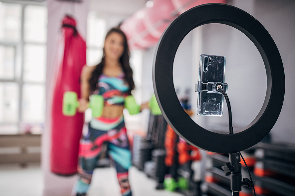 Fotografia de uma mulher gravando o seu treino em uma academia.